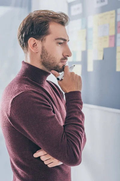 Vista lateral del pensativo hombre de negocios sosteniendo rotulador - foto de stock