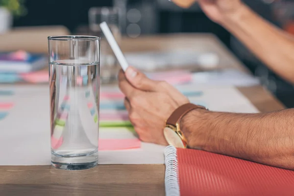 Selective focus of glass of water near businessman using digital tablet — Stock Photo