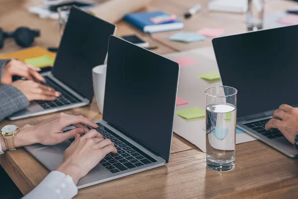 Vue recadrée des maîtres de mêlée à l'aide d'ordinateurs portables avec écran blanc dans le bureau — Photo de stock