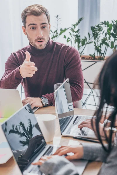 Selektiver Fokus eines gutaussehenden Geschäftsmannes, der mit dem Finger auf Mitarbeiter zeigt — Stockfoto