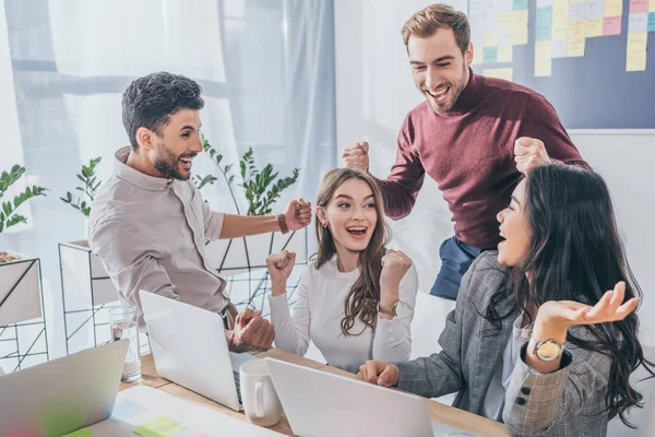 Happy multicultural businessmen and businesswomen celebrating triumph in office — Stock Photo