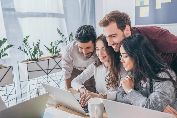 Uomini d'affari multiculturali felici e donne d'affari che guardano il computer portatile in ufficio — Foto stock