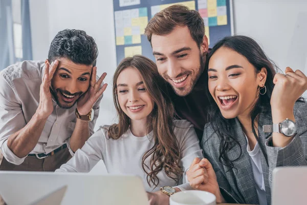 Fröhliche multikulturelle Geschäftsleute und Geschäftsfrauen, die im Büro auf Laptop schauen — Stockfoto