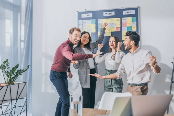 Excited multicultural businesswoman and businessman celebrating in office — Stock Photo