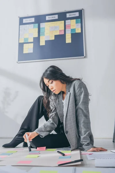 Beautiful asian scrum master sitting on floor near sticky notes — Stock Photo