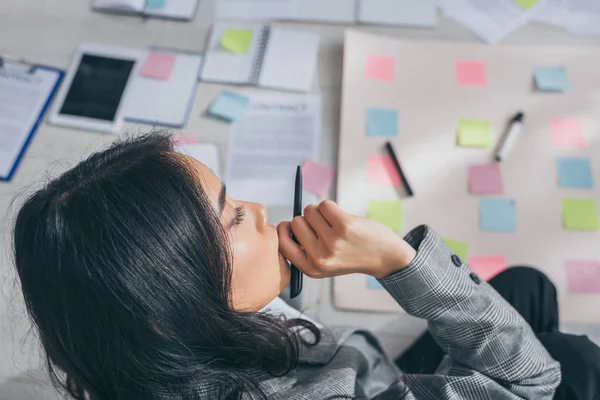 Overhead view of asian scrum master touching face while thinking in office — Stock Photo