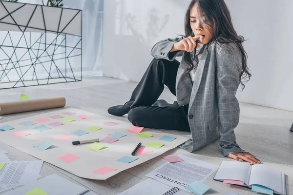 Attractive asian scrum master sitting on floor thinking in office — Stock Photo