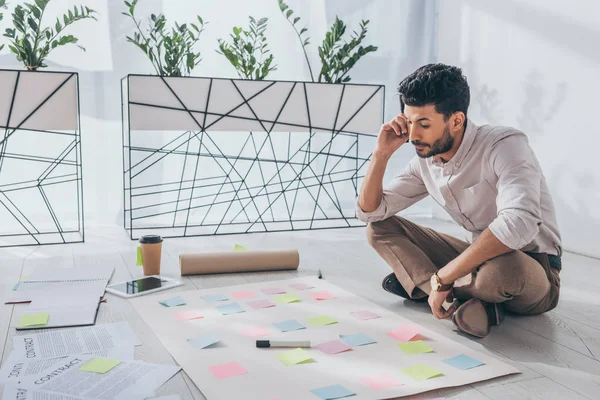 Bi-racial scrum master sitting on floor near sticky notes — Stock Photo