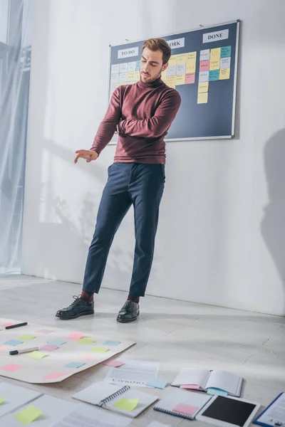 Selective focus of pensive businessman gesturing while looking at sticky notes on floor — Stock Photo