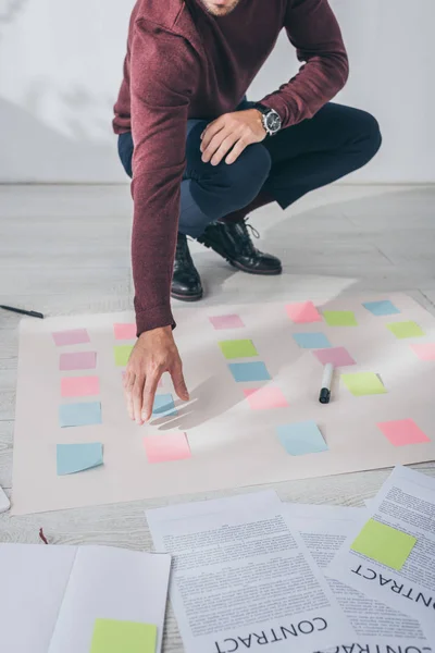 Cropped view of businessman with outstretched hand near sticky notes on floor — Stock Photo