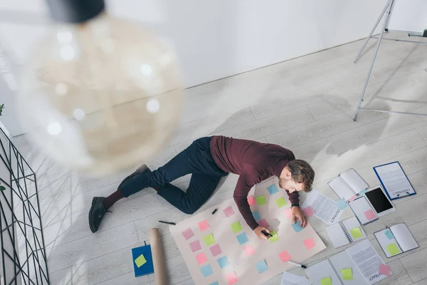 Top view of scrum master holding marker pen near sticky notes while lying on floor — Stock Photo
