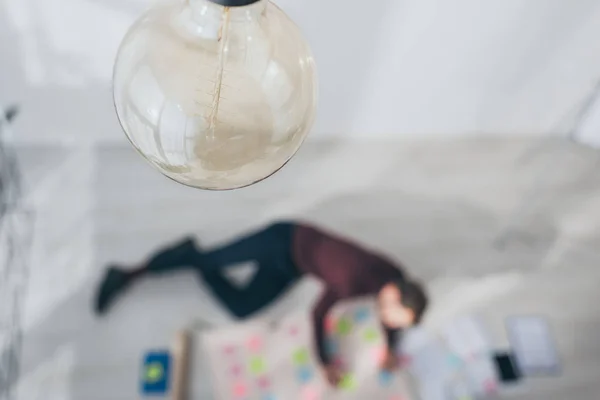 Selective focus of light bulb near scrum master lying on floor — Stock Photo