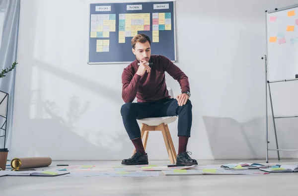 Thoughtful businessman sitting on chair and holding marker pen — Stock Photo