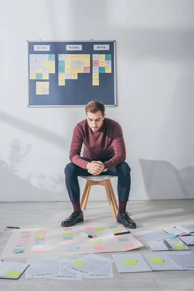 Schöner Gedrängemeister, der mit geballten Händen in der Nähe klebriger Noten sitzt — Stockfoto