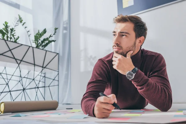 Nachdenklicher Gedrängemeister schaut weg, während er Filzstift in der Hand hält — Stockfoto