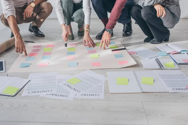Cropped view of scrum masters pointing with fingers at sticky notes on floor — Stock Photo