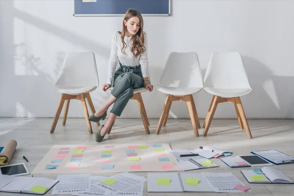Attractive scrum master sitting on chair near sticky notes on floor — Stock Photo