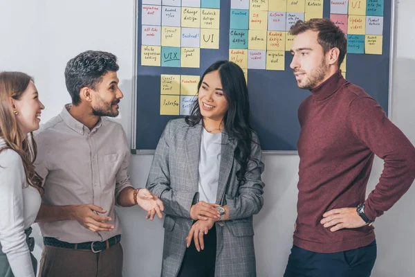 Cheerful multicultural coworkers smiling in office — Stock Photo