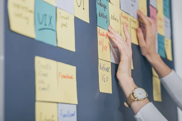 Cropped view of businesswoman touching sticky notes with letters in office — Stock Photo