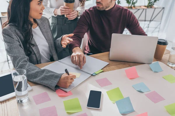 Abgeschnittene Ansicht von Geschäftsmann in der Nähe asiatischer Geschäftsfrau und Mitarbeiterin im Büro — Stockfoto