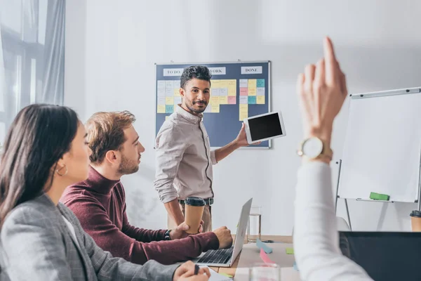 Selective focus of bi-racial scrum master looking at businesswoman with raising hand — Stock Photo