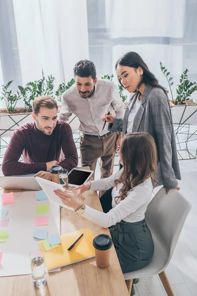 Compañeros de trabajo multiculturales mirando tableta digital en la oficina - foto de stock