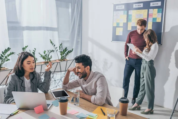 Asiático mujer de negocios utilizando portátil cerca mixta compañero de trabajo — Stock Photo