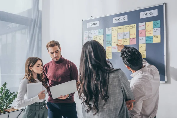 Selective focus of businesswoman standing near coworkers with gadgets — Stock Photo