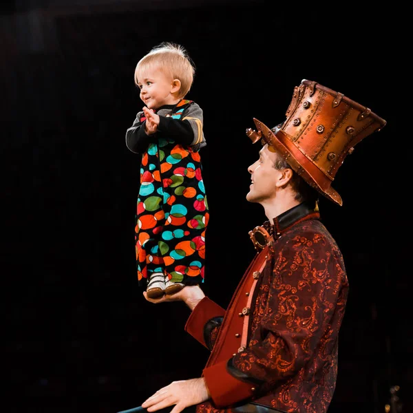 Happy man holding cute toddler kid in hand while performing in circus — Stock Photo