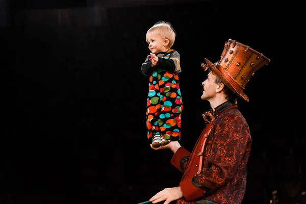 Happy man holding adorable toddler kid in hand while performing in circus — Stock Photo