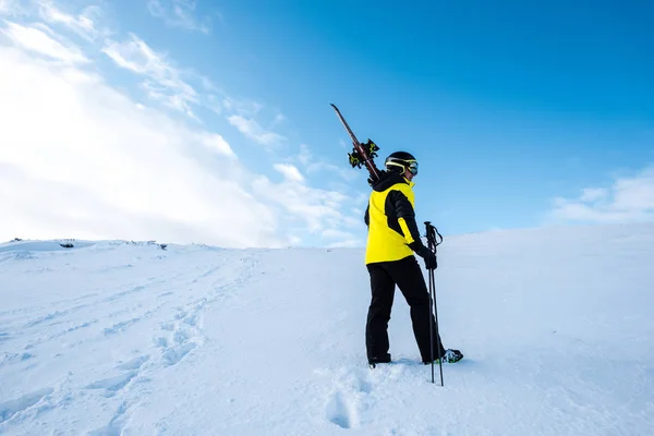 Sportsman in helmet standing with ski sticks on slope in wintertime — Stock Photo