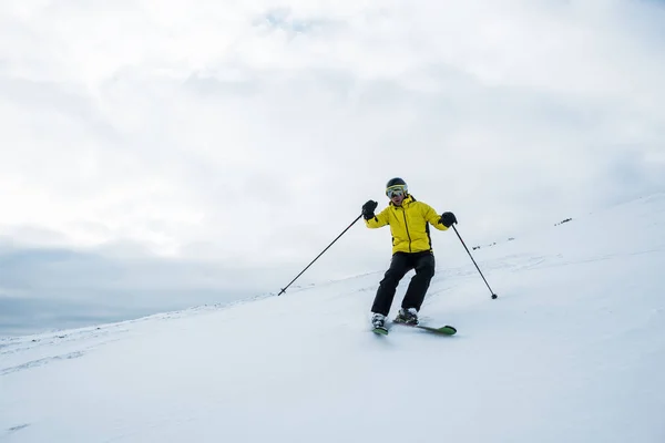 Active sportsman in helmet and goggles skiing on slope in wintertime — Stock Photo