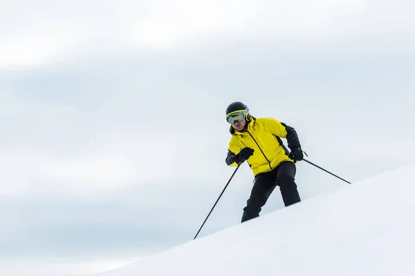 Лыжник в шлеме держит палки и катается на лыжах на склоне зимой — стоковое фото