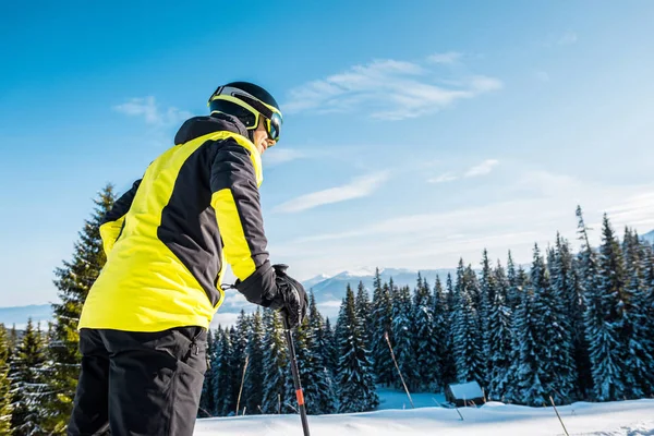 Vue à angle bas du skieur en casque debout sur la neige près des sapins — Photo de stock