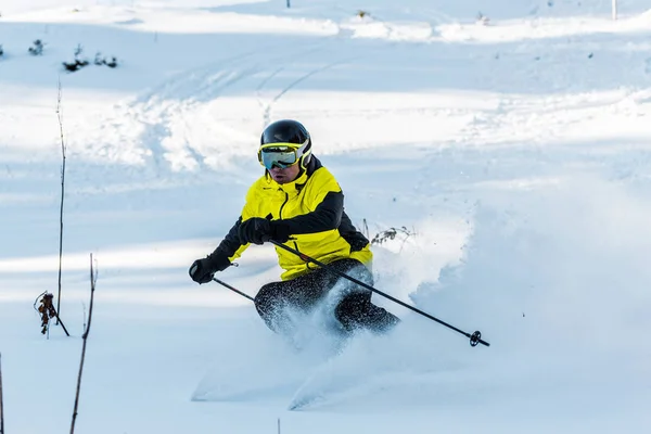 Skier in helmet holding ski sticks while skiing on white slope outside — Stock Photo