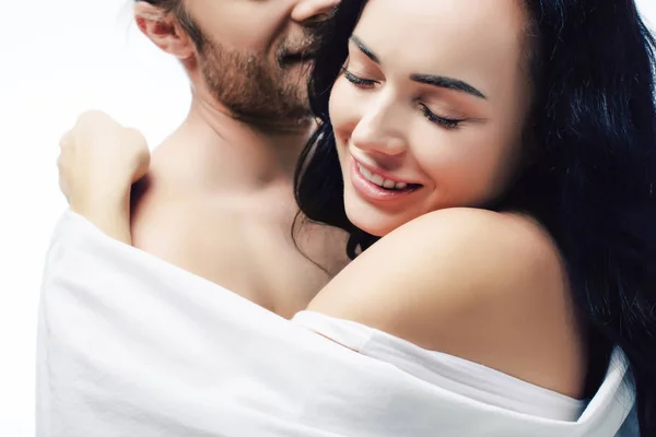 Happy sexy couple hugging in white sheets, isolated on white — Stock Photo