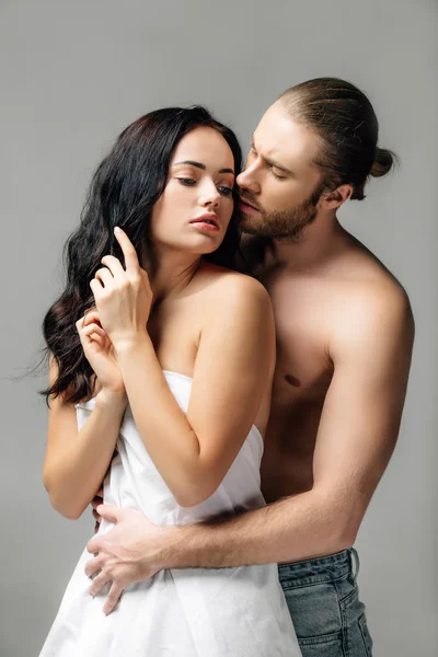 Passionate nude couple hugging in sheets, isolated on grey — Stock Photo