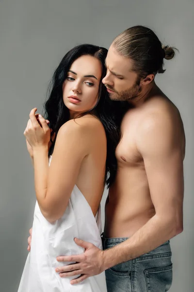Sensuale coppia nuda che abbraccia in lenzuola, isolata sul grigio — Foto stock