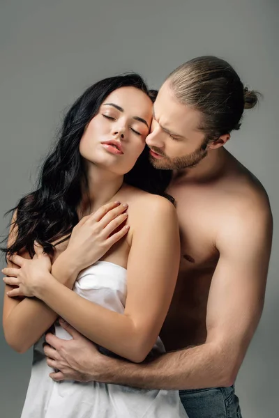 Tender nude couple hugging in sheets, isolated on grey — Stock Photo