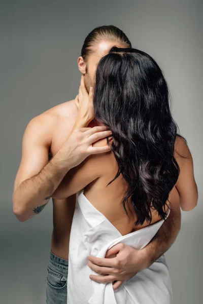 Apasionada pareja desnuda abrazándose y besándose en sábanas, aislada en gris - foto de stock