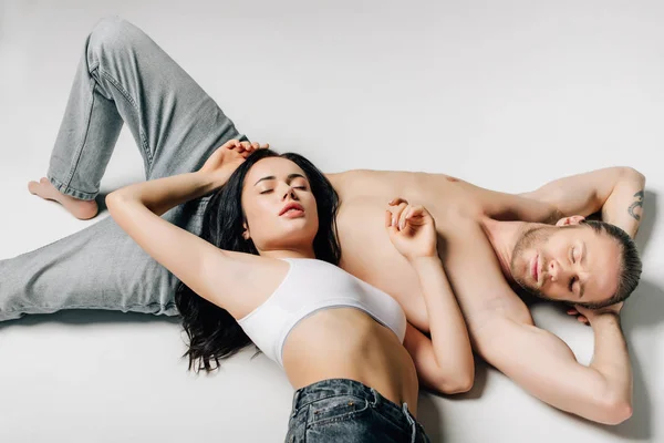 Beau couple tendre en sous-vêtements et jeans dormant sur blanc — Photo de stock