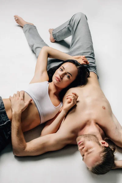 Beautiful sexy couple in underwear and jeans lying on white — Stock Photo