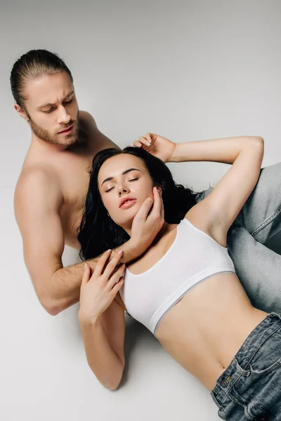 Beautiful passionate couple in underwear lying on white — Stock Photo