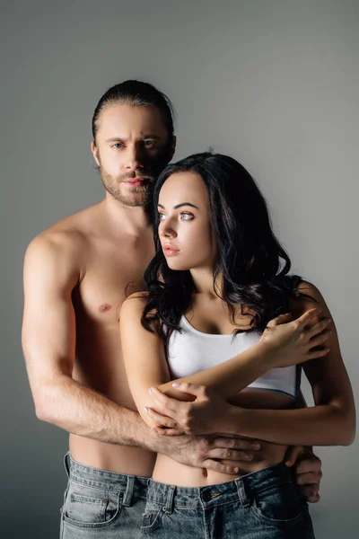 Shirtless young man hugging attractive woman isolated on grey — Stock Photo