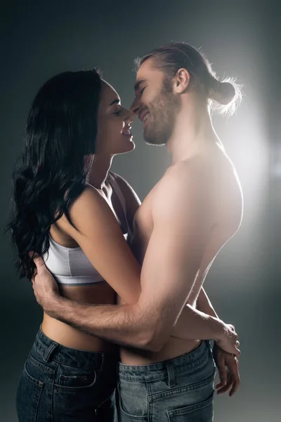 Улыбающаяся молодая пара обнимает серую с задним светом — стоковое фото