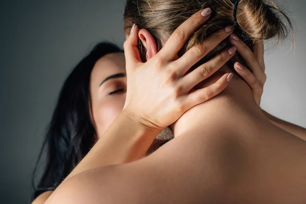 Pareja joven abrazándose y besándose en gris con luz de fondo - foto de stock