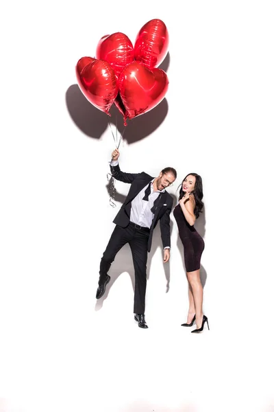 Belo casal alegre segurando balões em forma de coração vermelho no dia dos namorados no branco — Fotografia de Stock