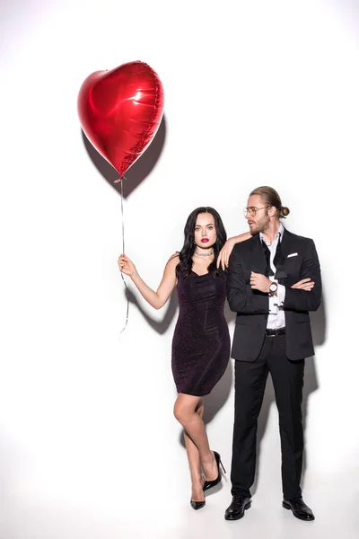 Young couple holding red heart shaped balloon on valentines day on white — Stock Photo