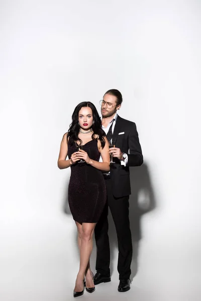 Young couple in suit and dress holding champagne glasses for valentines day on white — Stock Photo