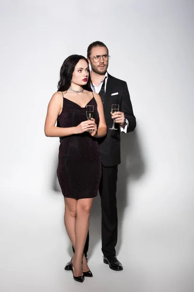 Hermosa pareja en traje y vestido sosteniendo copas de champán para el día de San Valentín en blanco - foto de stock